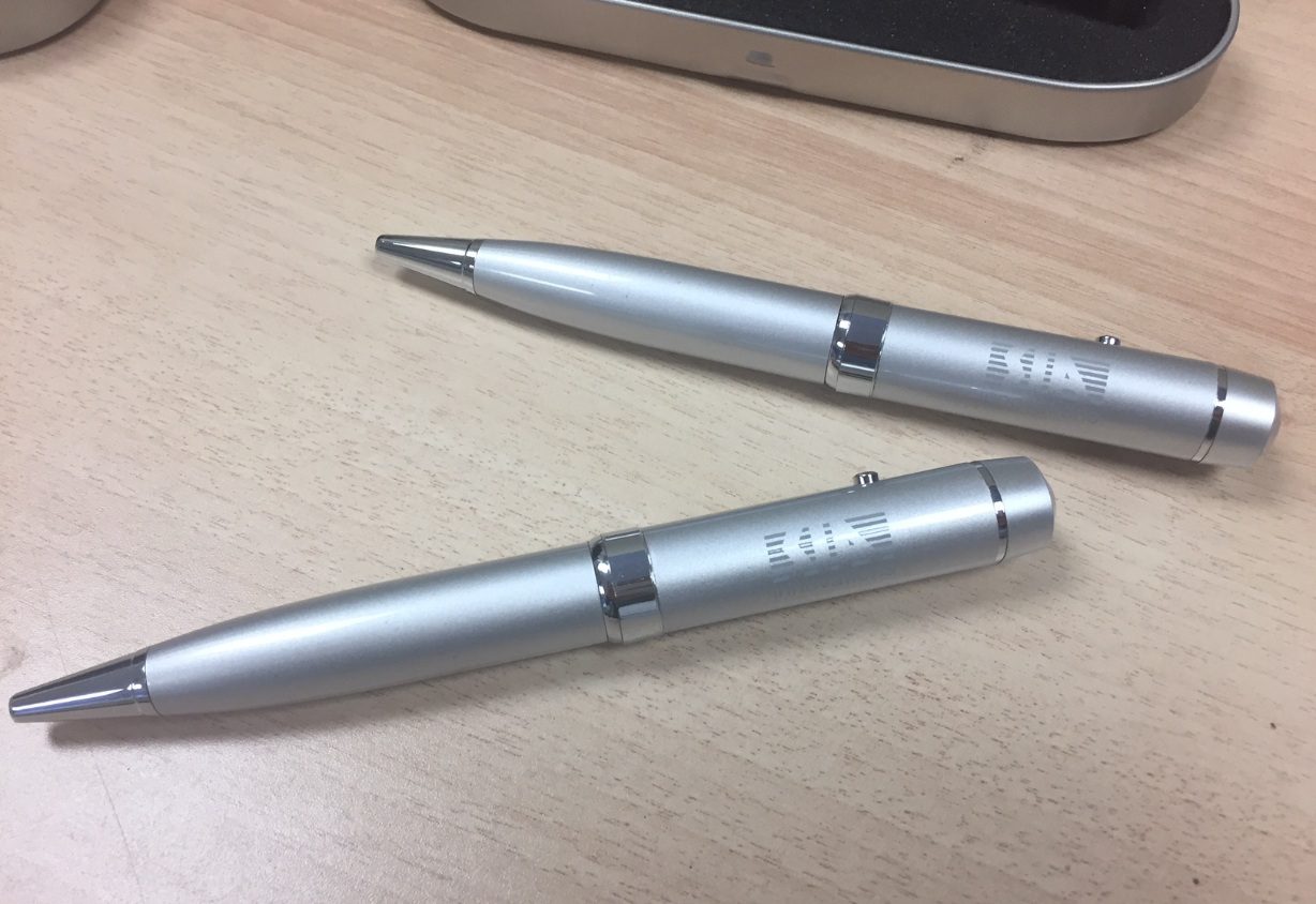 Two silver pens with USB drives placed on desk